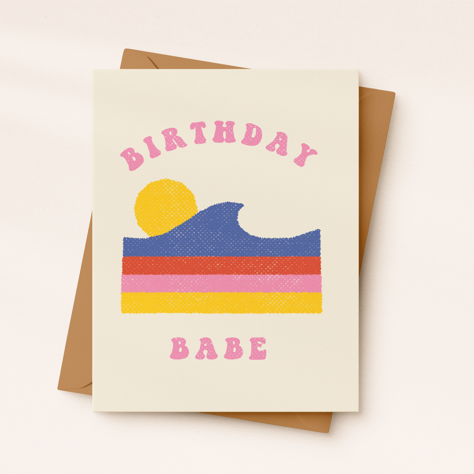 A cream-colored textured greeting card featuring a retro-style graphic of a blue cresting ocean wave layered over horizontal red, pink, and yellow stripes, with a yellow sun in the background. Pink curved block text reads "BIRTHDAY" at the top and "BABE" at the bottom, resting on a brown kraft envelope.